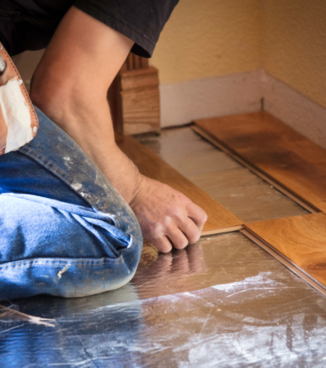 A man is working on a wooden floor for Atlanta Flooring Company in a room.